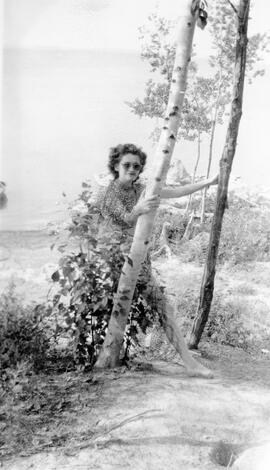 Femme s’appuyant sur deux arbres sur la plage du lac Malartic