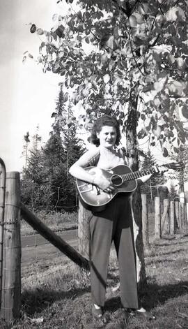 Vachon Rollande avec une guitare près d'une clôture