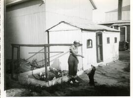 Claudine Vohl dans la cour de ses parents avec un chien et les poules