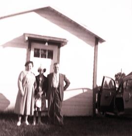 Un homme et une femme devant une voiture et une petite maison