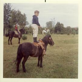 Yvon Ouellette debout sur un poney au chalet de Rolland Vohl