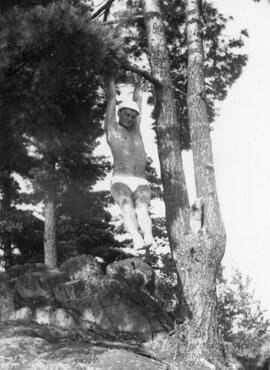 Homme en maillot de bain s’agrippant à un arbre