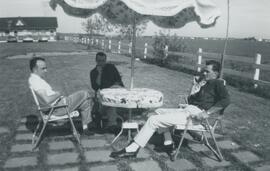 Trois hommes à une table près de l'eau