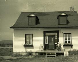 Maison devant avec homme assis sur la galerie, Mme Sauvageau - 46 rang St Denis Garneau