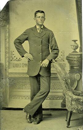 Jeune homme posant accoté sur une chaise