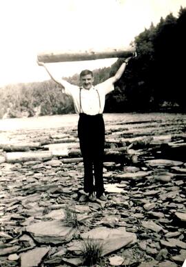 Marcel soulevant une bille de bois