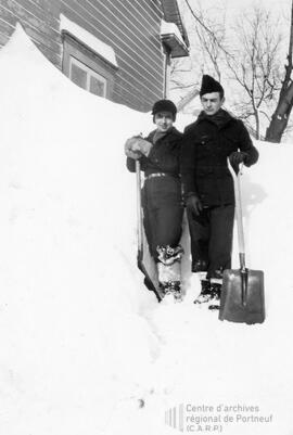 Deux hommes pelletant de la neige dehors en hiver