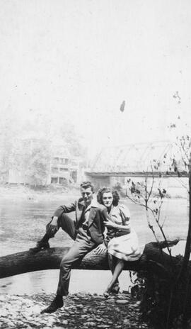 Un homme et une femme assis sur un arbre devant le pont de Saint-Casimir