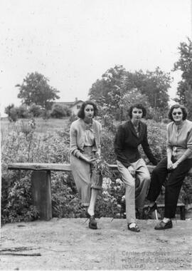 Trois dames assises sur la rambarde d’un pont