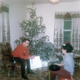 Un femme avec un vinyle et un homme devant un sapin de Noël