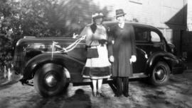 Deux nouveaux mariés près d'une voiture