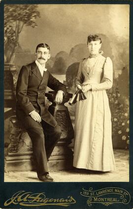 Photographie d’un couple (femme debout à l’éventail et homme assis)