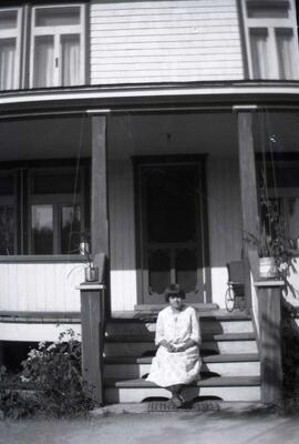 Femme inconnue assise sur les marches extérieures d'une maison
