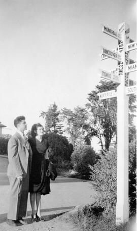 Couple regardant un poteau en bois directionnel