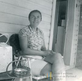 Femme assise devant l’entrée de sa maison