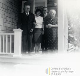 Quatre personnes devant l’entrée d’une maison