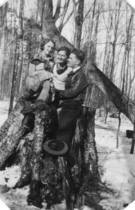 Trois personnes assises sur le tronc d’un arbre