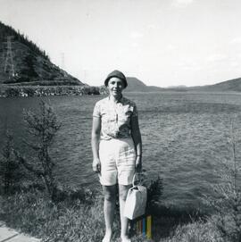 Femme devant un lac près de pylônes électriques