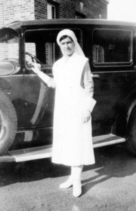 Une femme habillée en blanc près d'une voiture