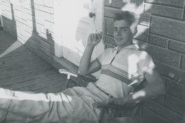 Homme sur une chaise devant l 'entrée d'une maison