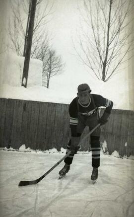 Vachon Adélard habillé en joueur d'hockey sur une patinoire