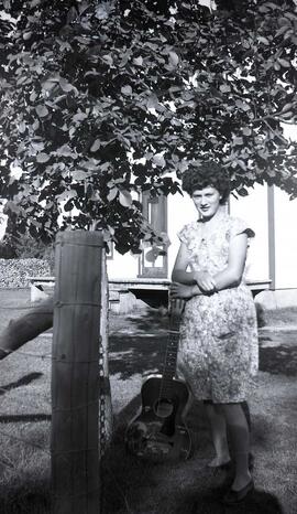 Vachon Rollande accotée sur une guitare dans la cour d'Arthur Vachon