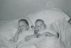 Deux bébé sur un lit  dont un avec un marteau- Août 1957