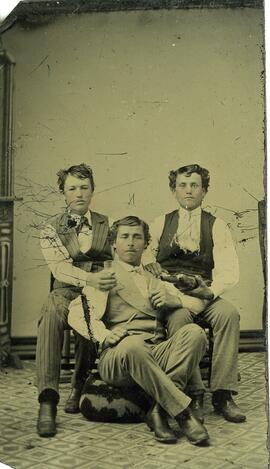 Trois jeunes jeunes hommes posant avec une bouteille et un verre