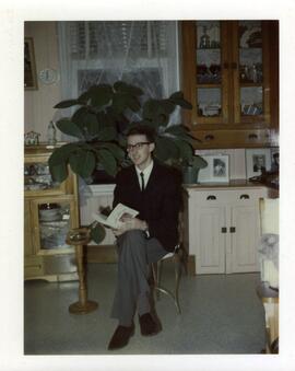 Rémy Vohl avec un livre dans la maison de ses parents