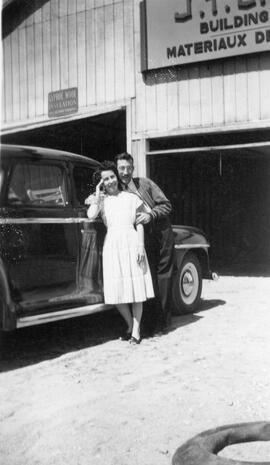 Un homme et une femme à coté d’une voiture devant un garage