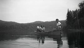 Deux hommes et une femme inconnus dans un canot sur un lac