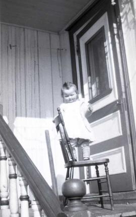 Un bébé debout sur une chaise sur une galerie