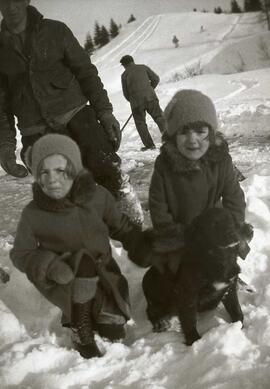 Deux enfants avec un chien et deux hommes inconnus jouant dans la neige