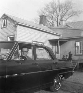 Femme dans une voiture devant une maison