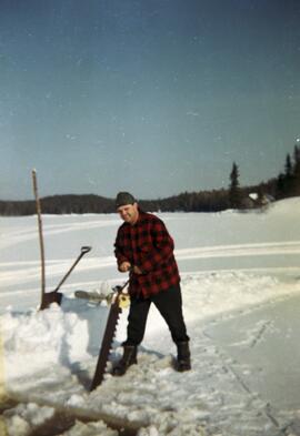 Un homme fait un trou dans la glace