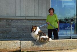 Claudine Vohl avec son chien devant le magasin Vohl