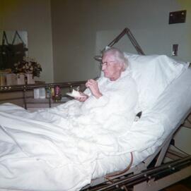 Une femme dans un lit d’hôpital en train de manger un part de gâteau