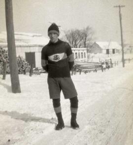 Jeune homme en habit de hockeyeur sur le bord d'une route en hiver