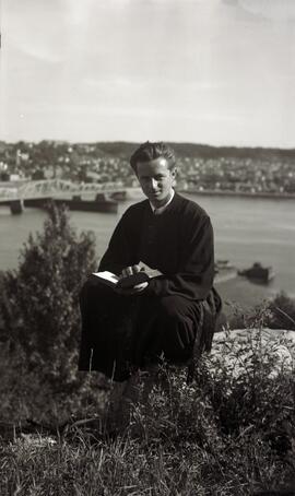 Un homme lit un livre près d’un pont