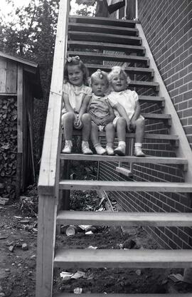 Trois petites filles assises dans un escalier extérieur