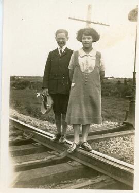 Jeune fille et jeune homme sur voie ferrée (possiblement vue du 3e rang à l'arrière et une vache en pâturage - Grondines)