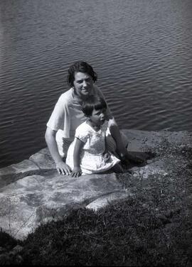 Une femme et un enfants inconnus assis sur une roche près de l'eau