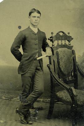 Jeune homme posant accoté sur une chaise