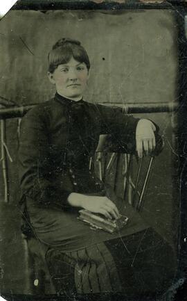 Jeune femme posant assise sur une chaise avec un livre