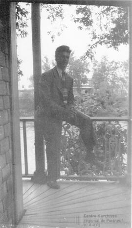 Un homme assis sur la rambarde d’une terrasse