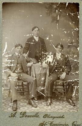 Photographie de trois jeunes hommes dont Roger Dusablon (deux assis, un debout)