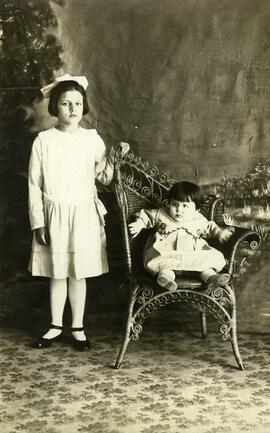 Photographie d’une jeune fille debout et d’un enfant assis