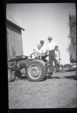 Deux hommes et deux enfants non identifiés sur un tracteur