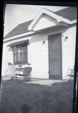 Une maison blanche avec trois chaises à l'avant