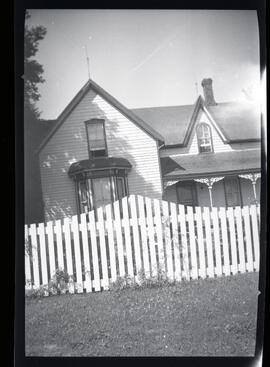 Une maison blanche derrière une clôture